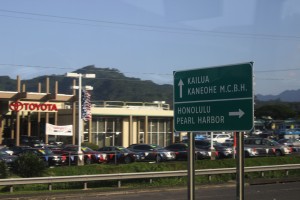 05 A highway road sign for Kailua, Kaneohe Marine Corps Base Hawaii MCBH, Honolulu, and Pearl Harbor in front of a Toyota dealership on O'ahu in Hawaii Photo Credit Zack Neher